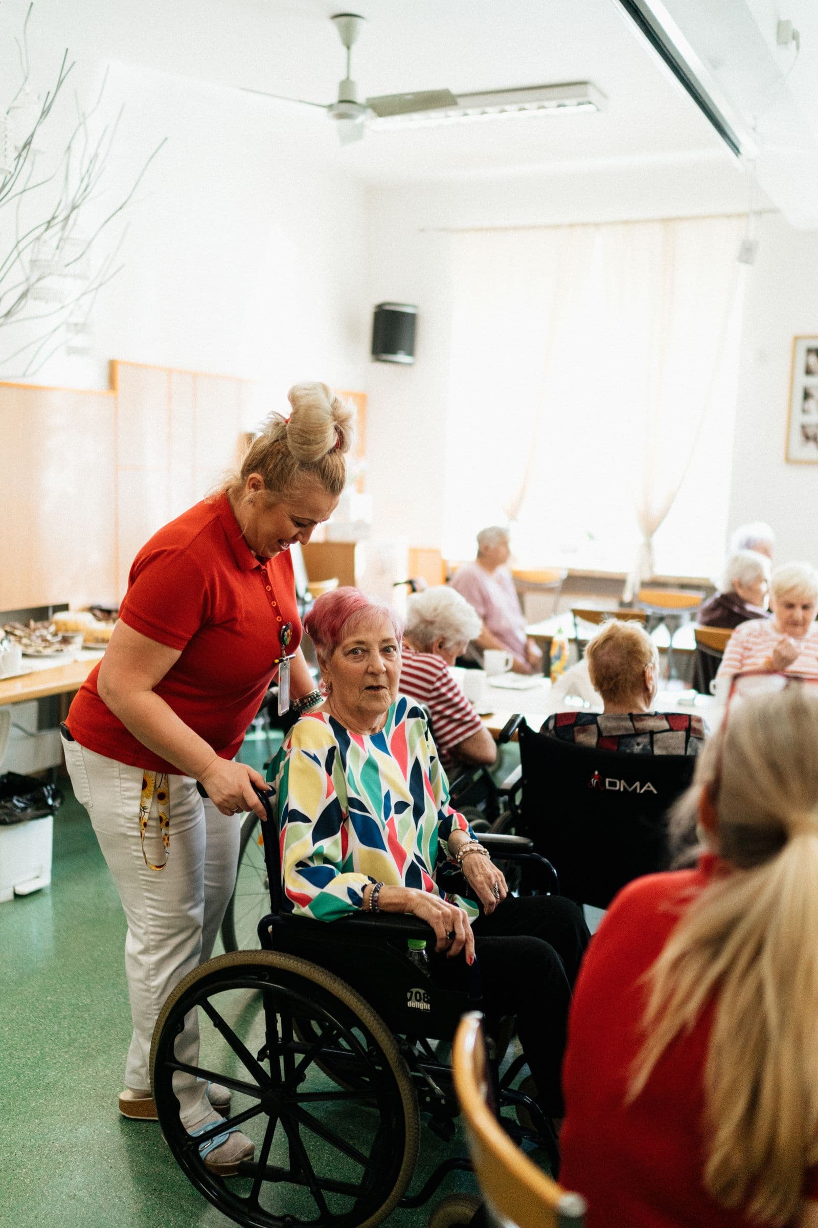 En glad medarbeider og en eldre kvinne i et sosialt fellesskap